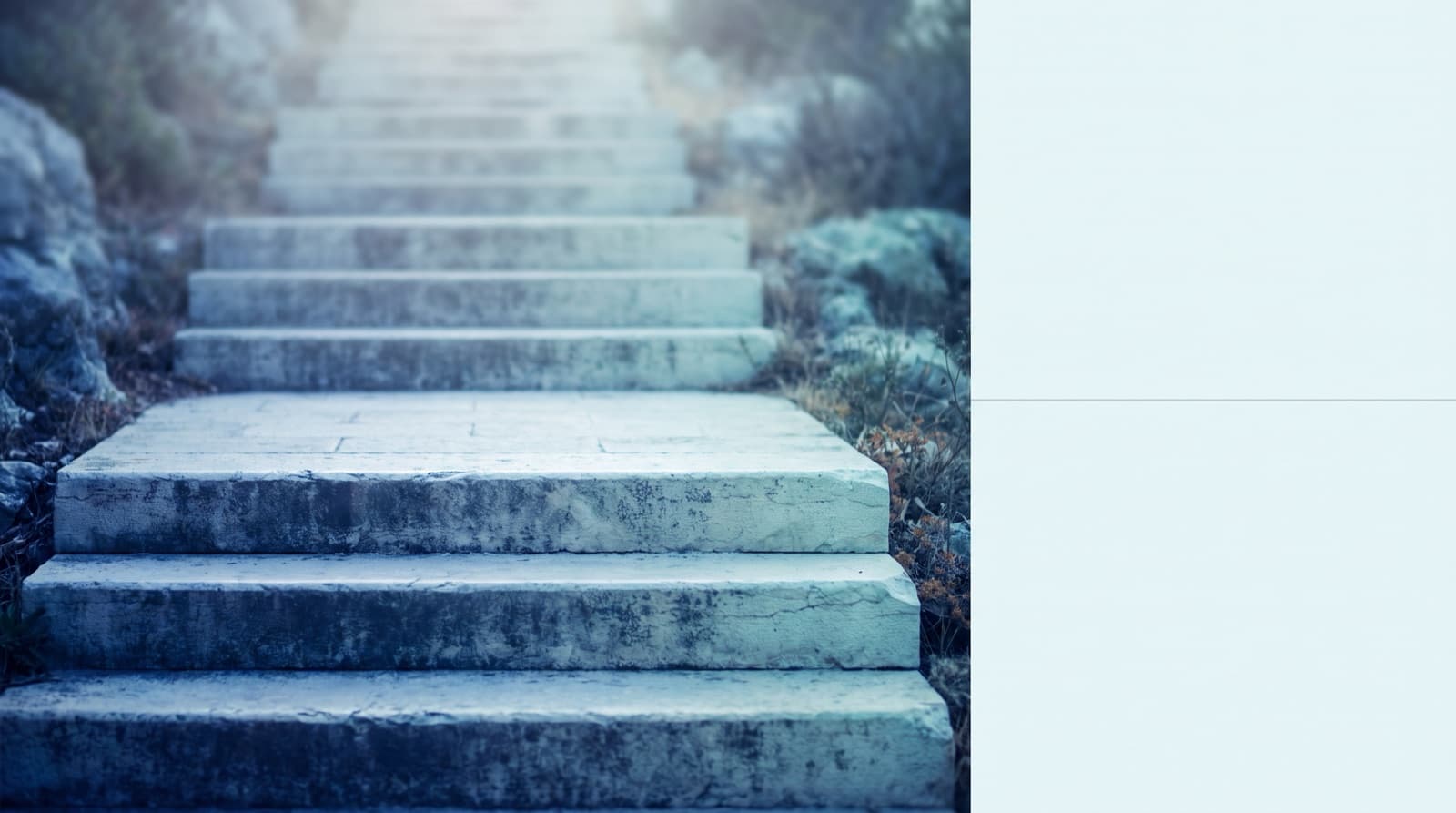 Wide, shallow stone steps climbing toward bright light, framed by rock and scrub in cool blue tones.